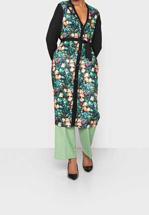 Floral patterned long cardigan in black and vibrant colors, belted at the waist, paired with light green wide-leg pants and black heels.
