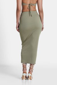 Gonna maxi a coste di colore verde oliva con un design aderente, caratterizzata da spacchi laterali e abbinata a sandali bianchi con tacco alto e fasce.