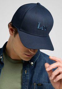 Marineblauwe baseballcap met geborduurd "Lee" logo in contrasterend blauw. Gestructureerd ontwerp met een soepele textuur en een gebogen klep.
