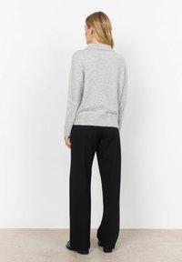 Grau Sweatshirt mit Kragen, geripptem Saum und langen Ärmeln, kombiniert mit schwarzen weit geschnittenen Hosen und schwarzen Schuhen.