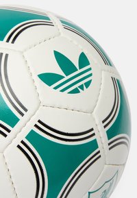 Hvid fodbold med grønne og sorte detaljer, en struktureret overflade, indviklet syning og et Adidas-logo, der står fremtrædende.