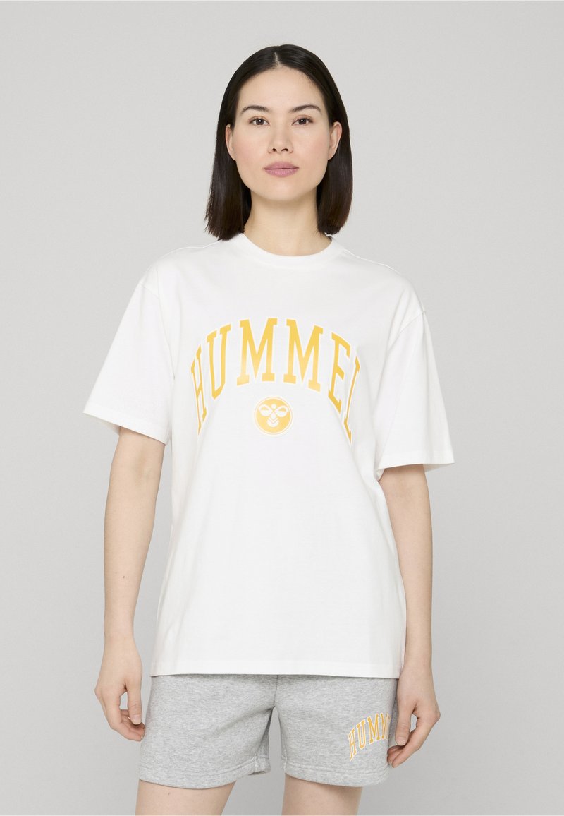 T-shirt en coton blanc avec un graphique et un logo "HUMMEL" jaune sur la poitrine, assorti à un short gris avec un logo assorti en jaune.