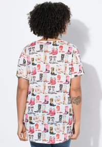 Korte mouwen, lose-fitting t-shirt in lichtgrijs met een herhaald patroon van kleurrijke laarzen, met verschillende stijlen en ontwerpen.