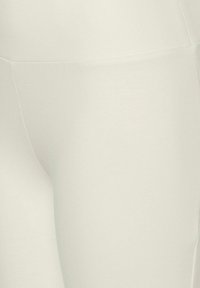 Vita, stretchiga leggings med en mjuk textur och sömlös design. Materialet är lätt och åtsittande, lämpligt för aktiv användning.