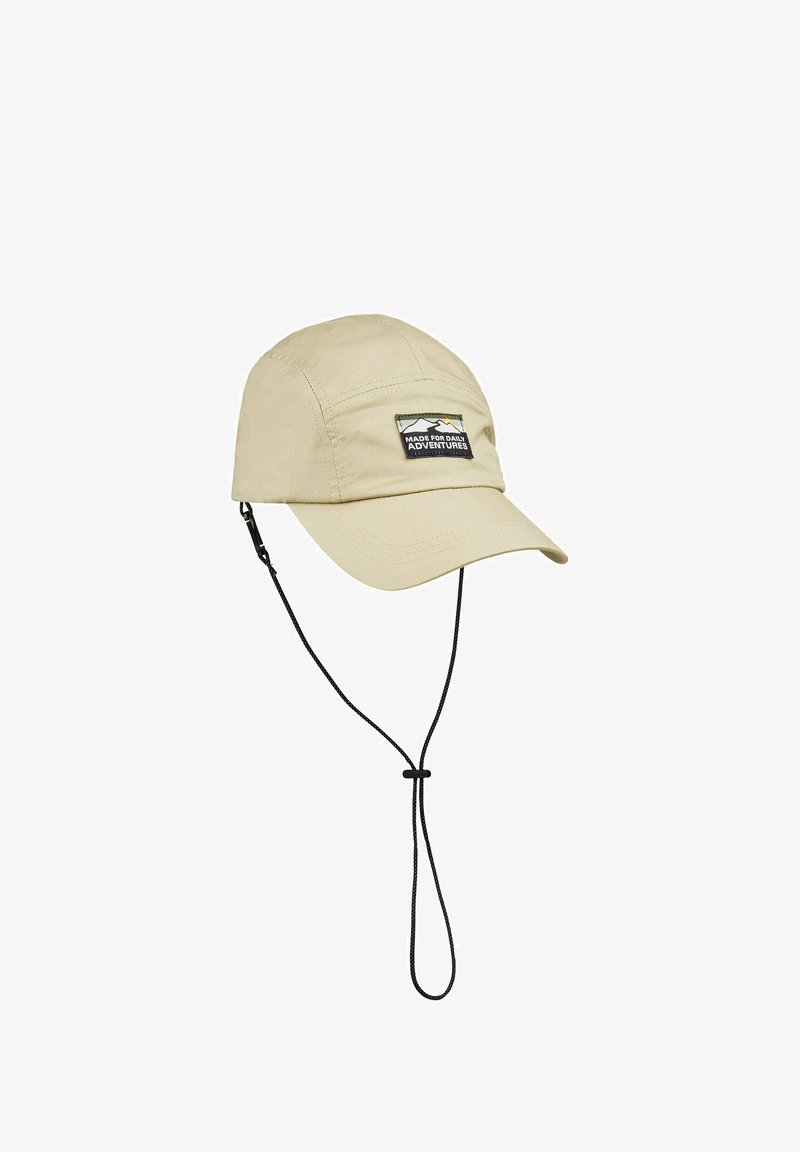 Beige cap made of lightweight material, featuring a curved brim, adjustable chin strap, and a patch with "Made for Daily Adventures" text.
