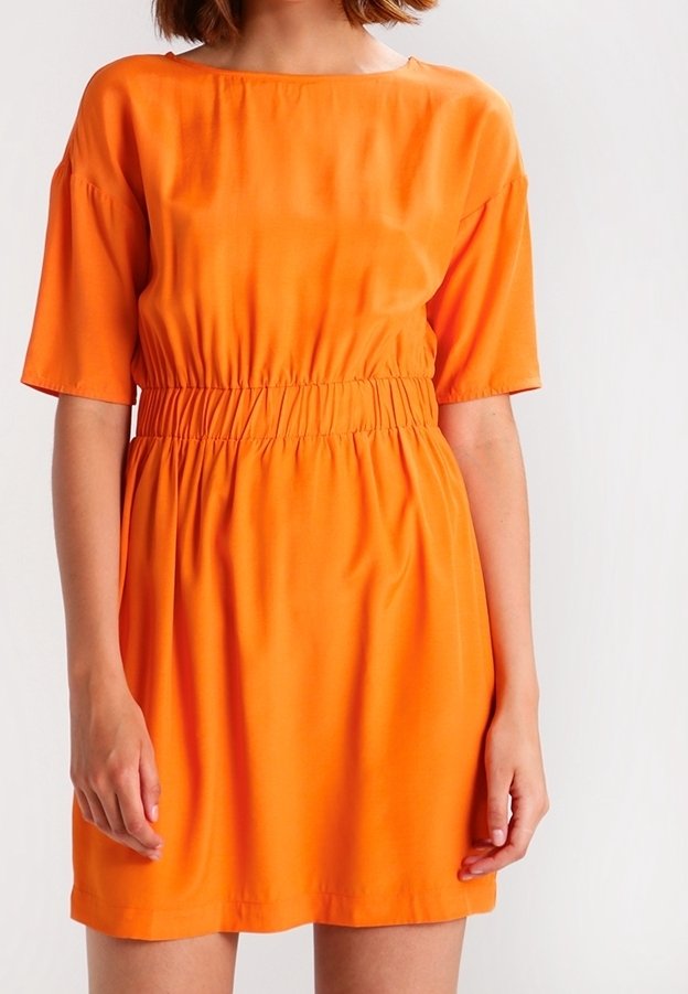Kort ärmad orange klänning i mjukt tyg, med resårmidja och en avslappnad passform. Enkel, knälång design.