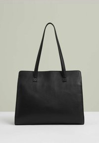 Svart läder tote-väska med hög, platt form och slät yta. Har långa handtag och en minimalistisk design utan synlig hårdvara.