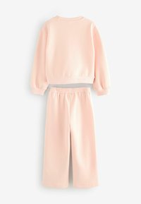 Ensemble de sweatshirt rose pâle et de jogging assorti. Tissu doux, poignets et taille côtelés, coupe décontractée, poches latérales sur le pantalon.