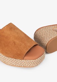 Sandalias de ante marrón con la punta descubierta y plataforma de yute trenzado, que cuentan con una plantilla de cuero suave y una suela texturizada de color claro.