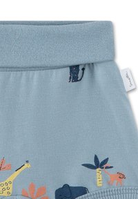 Light blue fabric with an elastic waistband features animal and plant designs in orange, navy, and yellow, including a giraffe and monkey.