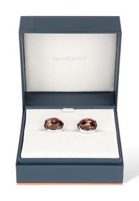 Silver-tone cufflinks with a circular design featuring a brown and beige patterned background, presented in a navy blue box with a textured white interior.