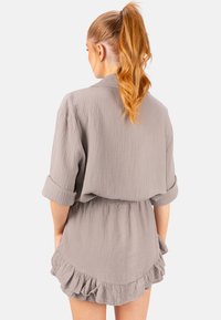 Robe grise texturée à coupe décontractée, avec des manches retroussées et un ourlet volanté. Fabriquée en tissu léger, avec une taille élastique pour le confort.