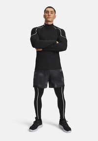 Black long-sleeve top with reflective accents, paired with black and gray patterned shorts and black fitted leggings. Black athletic shoes.