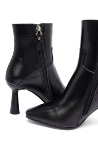 Stivaletti neri in pelle con punta affusolata e tacco a stiletto di 10 cm, caratterizzati da cerniere laterali e una finitura liscia e lucida.
