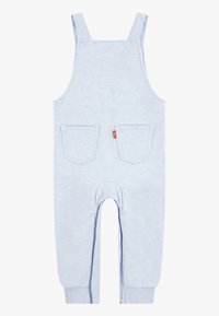 Mono de algodón azul claro con tirantes, dos bolsillos frontales, puños acanalados y una costura centrada en la parte posterior.