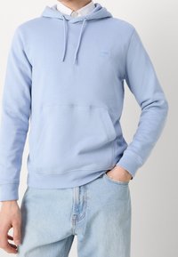 Svetle modrá mikina s kapucí z měkkého materiálu, s klokáním kapsou, stahovací kapucí a malou nášivkou s logem vpředu.