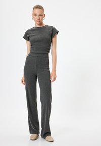 Zweiteiliges Outfit aus dunkelgrauem Rippstoff. Kurzärmliges Oberteil mit Rundhalsausschnitt und eng anliegende Hose mit weit auslaufenden Beinen. Glatte Textur.