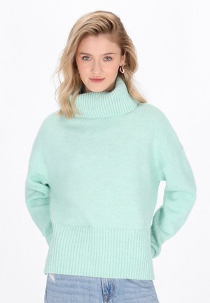 Mint green knitted sweater with a high ribbed collar, dropped shoulders, and a ribbed hem. Soft texture and relaxed fit.