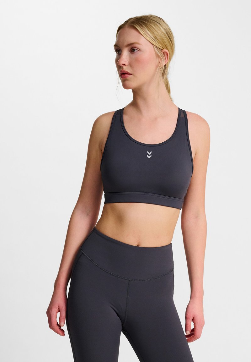 Donkergrijze sportbeha met een gladde, rekbare textuur, voorzien van een ronde hals en dunne straps, gecombineerd met bijpassende high-waisted leggings.