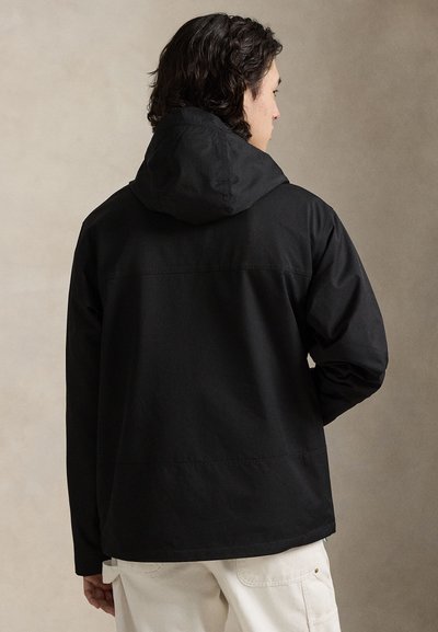 Svart hettejakke med glatt tekstur og avslappet passform. Har en sømløs bakside og minimalistisk stil.
