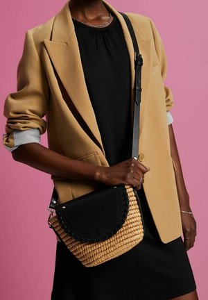 Yhdistelmä olkakorua, jossa on kudottua olkea ja mustaa nahkaa, kaareva läppä, kudottu kuvio ja metallinen olkahihna.