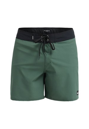 Shorts de bain verts avec une ceinture élastique noire. Dotés d'une fermeture à cordon et d'une petite étiquette logo sur l'ourlet inférieur. Texture lisse.