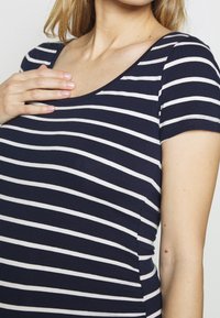 Mörkblå och vitrandig kortärmad tröja med rundad halsringning, tillverkad av mjukt tyg, med en figurnära siluett och lätt stretch.