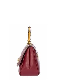Sac à main en cuir rouge avec une finition texturée, quincaillerie dorée et une poignée en bambou. La vue de côté révèle une forme structurée avec un design plissé.