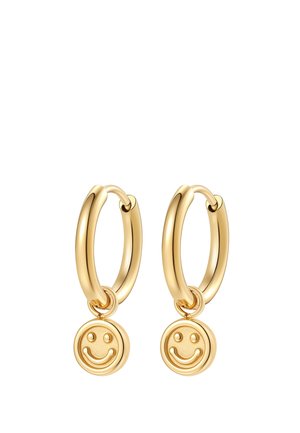 Pair of gold hoop earrings with small smiling face charms hanging from each hoop on a white background.