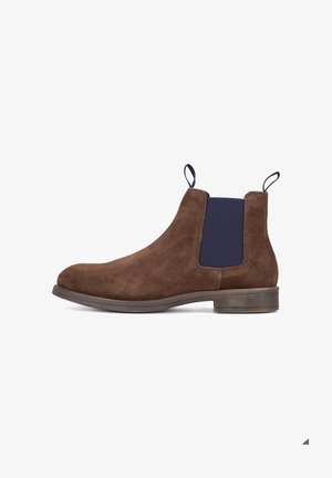 Brauner Chelsea-Stiefel aus Wildleder mit elastischen seitlichen Einsätzen in Marineblau, Zuglasche an der Ferse, abgerundete Spitze und niedriger Absatz. Glatte Textur und elegantes Design.