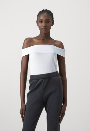 Valge õlavarrelt avatud ribistatud bodysuit, millele on paigutatud tumedashall ribistatud püksid. Sile tekstuur, istuv disain, elastne vöökoht, casual stiil.