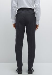 Skräddarsydda grå byxor med smal passform, tillverkade i ett mjukt tyg, med bakfickor och platt frontdesign, stylade med en vit långärmad skjorta.