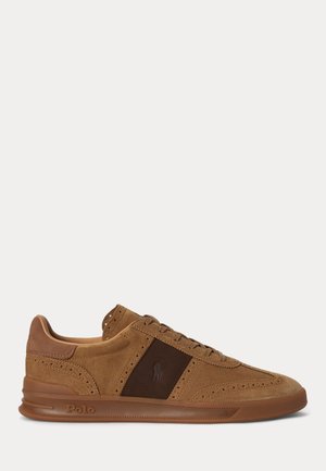 Baskets basses en daim marron avec détails perforés, panneau latéral marron foncé et logo Polo sur la semelle et le côté.
