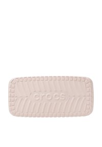 Jasnoróżowy but Crocs z grubą, teksturowaną podeszwą. Posiada zaokrąglone krawędzie i wytłoczone logo "crocs". Zaprojektowany z otworami wentylacyjnymi.