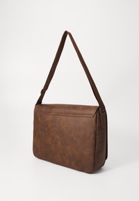 Sac bandoulière marron en cuir synthétique avec une texture lisse, une forme rectangulaire plate, une sangle d'épaule réglable et une fermeture éclair supérieure.