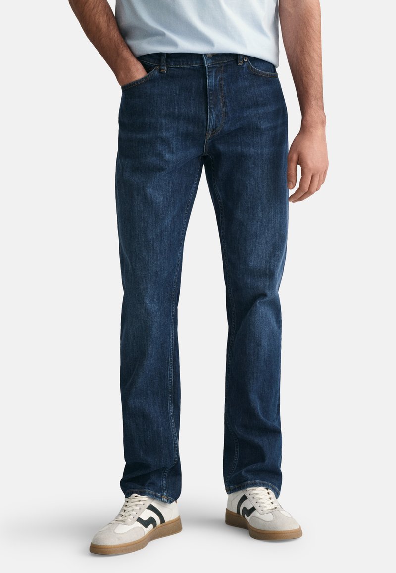 Jeans din denim de culoare albastru închis, cu croială dreaptă, design cu cinci buzunare și o ușoară decolorare. Asortați cu adidași alb-crem cu accente negre.