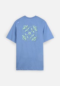 T-shirt bleu à manches courtes avec un motif floral et de feuilles vertes centré dans le dos et un petit patch près de l'épaule.