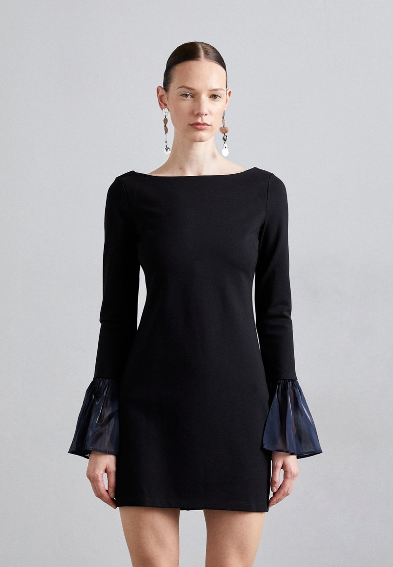 Black dress with long sleeves featuring sheer, flared cuffs. The fabric is smooth, and the neckline is wide and flat, providing a sleek silhouette.