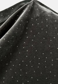 Tissu en velours noir comportant de petits points argentés, espacés de manière uniforme, créant un motif texturé sur la surface lisse.