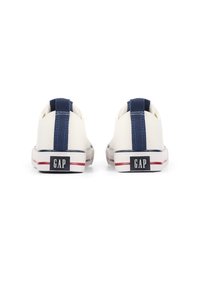 Weiße Segeltuch-Sneaker mit marineblauem Akzentstreifen, Gummisohle und GAP-Logo auf der Ferse. Mit einer Schlaufe für einfaches Anziehen.