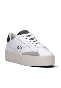 Sneaker bassa bianca con suola beige, toppa in suede grigia sulla punta, tassello nero sul tallone, lacci bianchi e logo a stella nera con "ΔX" sul lato.