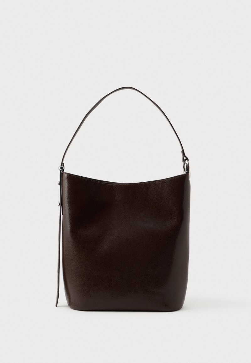 Bolsa de ombro em pele castanha com uma textura suave, forma arredondada e uma alça longa. Apresenta um design minimalista e acessórios de metal prateado.