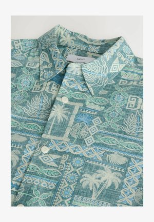 Trumpomis rankovėmis marškiniai su sagomis, turkio ir mėlynos spalvos tropiniais geometriniais raštais ir palmių motyvais, sulankstyti taip, kad matytųsi apykaklė ir sagos.