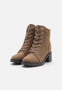 Bottines en simili cuir marron avec un laçage à l'avant, bout rond, talon bloc et clous décoratifs sur le col. Texturé et rembourré.