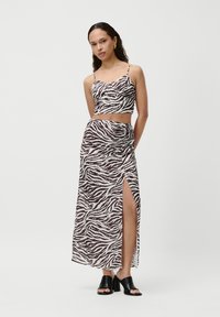 Hnedo-biely zebrový vzor v dvojdielnom sete, ktorý obsahuje crop top s tenkými ramienkami a maxi sukňu s vysokým rozparkom, zosilňujúcu viditeľnosť nôh.