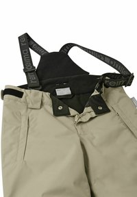 Beżowe spodnie narciarskie z regulowanymi czarnymi szelkami, wyposażone w zamek błyskawiczny i zatrzask, boczne kieszenie oraz gładką, wodoodporną teksturę.