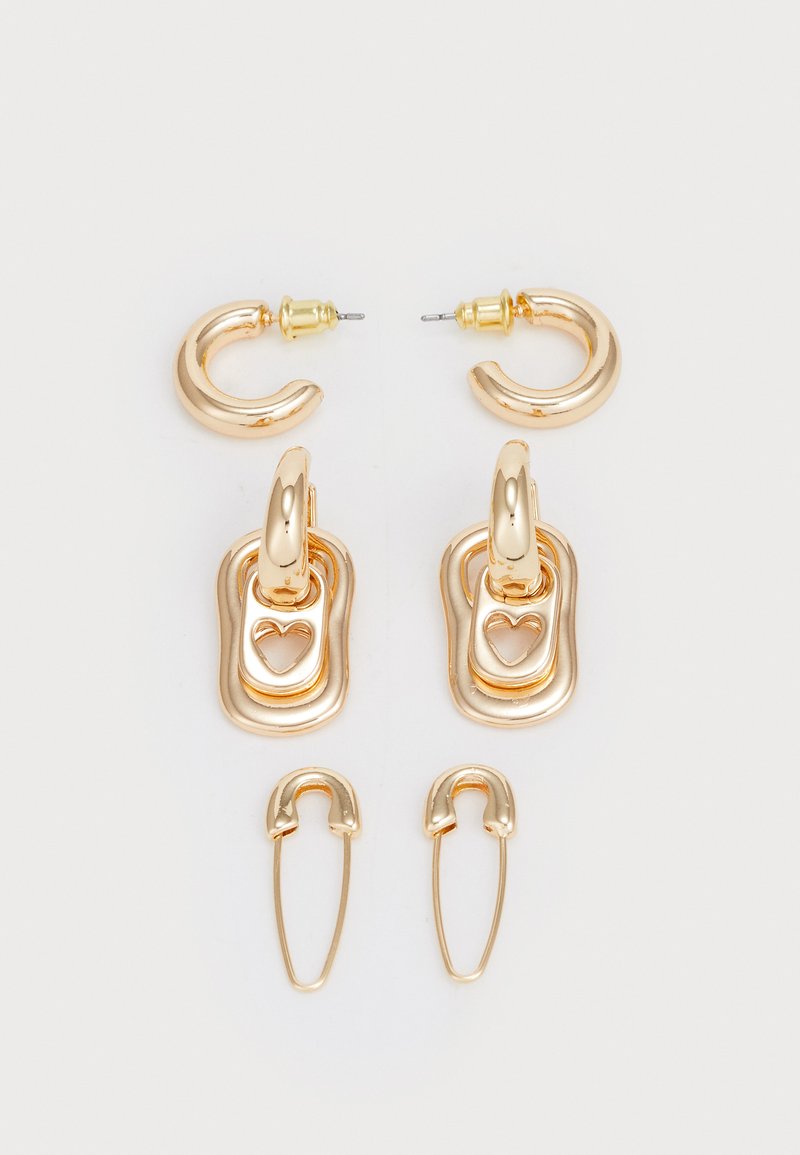 Sett med gullfargede øredobber som inkluderer hoops og charms. Texturerte overflater med hjerteformede utskjæringer og en sikker lukkeanordning.