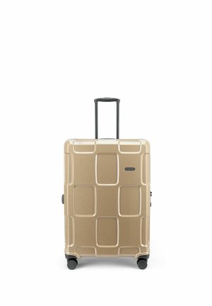 Valise rigide couleur beige avec motifs géométriques, quatre roues et poignée télescopique noire prolongée.