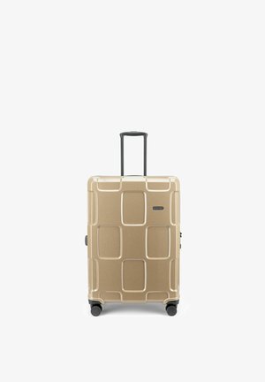 Valise rigide couleur beige avec motifs géométriques, quatre roues et poignée télescopique noire prolongée.