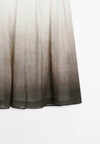 Ombre maxi kjol med en mjuk, genomskinlig textur som övergår från ljus grädde till mörkgrå vid fållen, med en flödig design och utan synliga knäppningar.